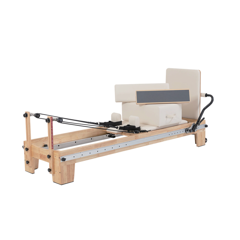 A wooden Pilates reformer machine with cream-colored foam padding, a black handlebar, and a metal guide rail, shown against a plain white background.